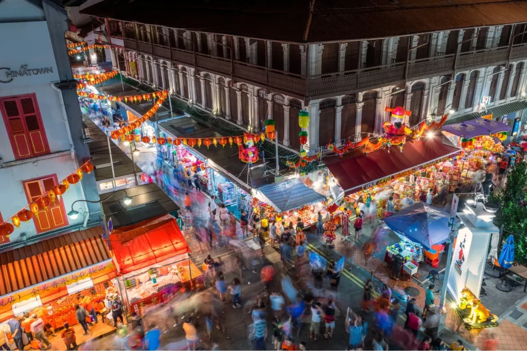 Nachtmarkt in Singapurs Chinatown, geschmückt mit Laternen, voller Menschen und farbenfroher Stände