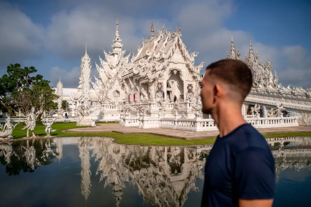 Wat Rong Khun in Chiang Rai, der berühmte weiße Tempel mit beeindruckenden Details und spiegelnder Wasserfläche, ein Muss beim Thailand Backpacking.