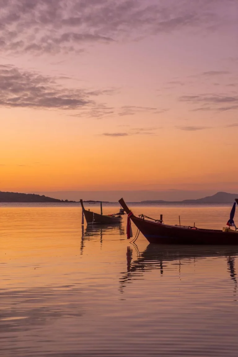 Sonnenuntergang auf Koh Samui in der besten Thailand Reisezeit mit Long Tail Booten im Vordergrund.