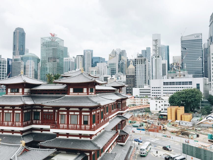 From above of old Asian house facades behind modern multistory dwelling buildings under cloudy sky in town