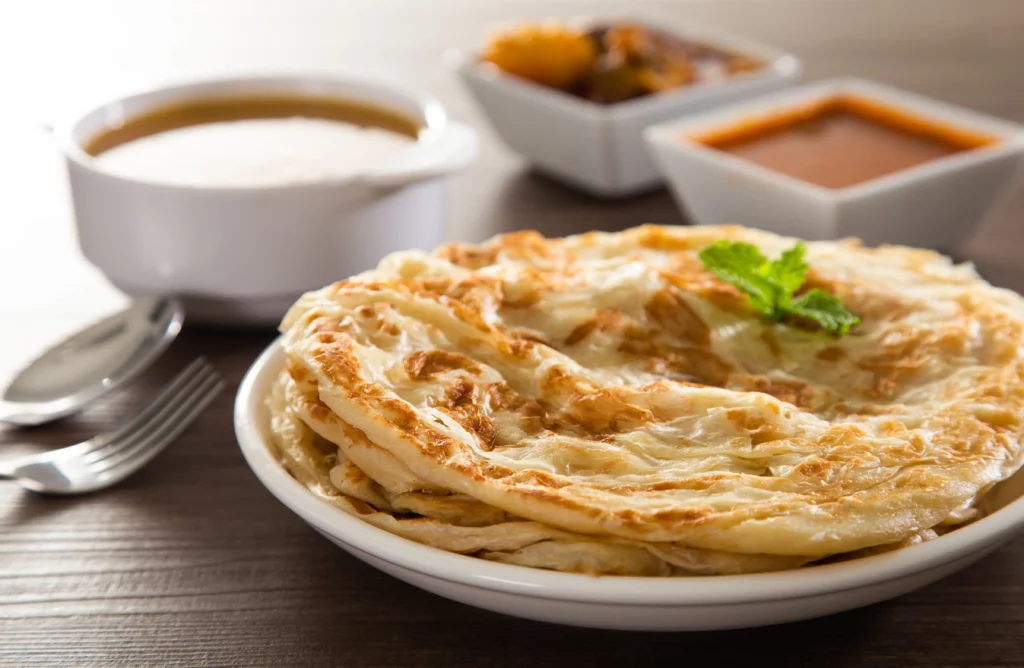 Frisches Roti Prata mit verschiedenen würzigen Currys, serviert zum Frühstück in Singapur