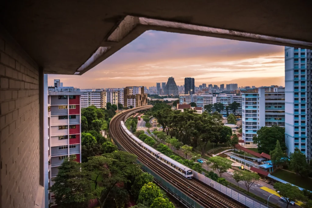 MRT-Zug in Singapurs Stadtlandschaft bei Sonnenuntergang mit modernen Gebäuden im Hintergrund