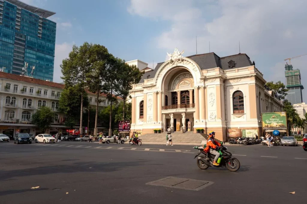 Ein Oldtimer-Motorrad fährt am beeindruckenden Opernhaus von Ho-Chi-Minh-City vorbei und hebt dessen Kolonialarchitektur hervor.