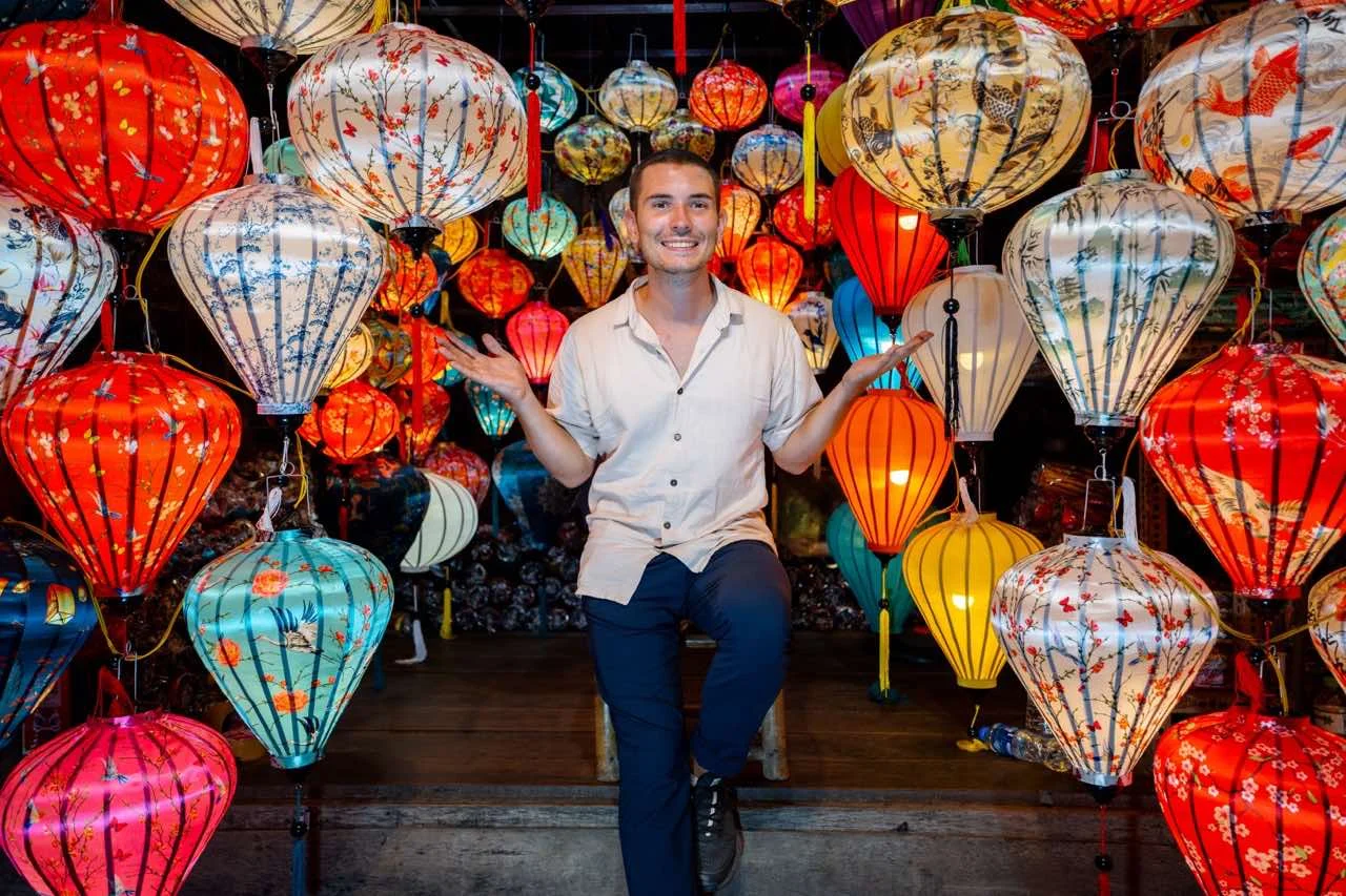 Jonathan strahlt inmitten der leuchtenden Laternen auf dem farbenfrohen Markt von Hoi An auf der Vietnam Reise.