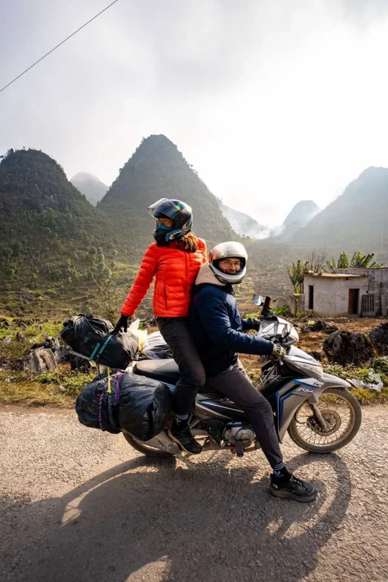 Clara und Jonathan befahren kurvenreiche Straßen auf einem Motorrad, umgeben von atemberaubenden Bergpanoramen – Kurzurlaub 2025.