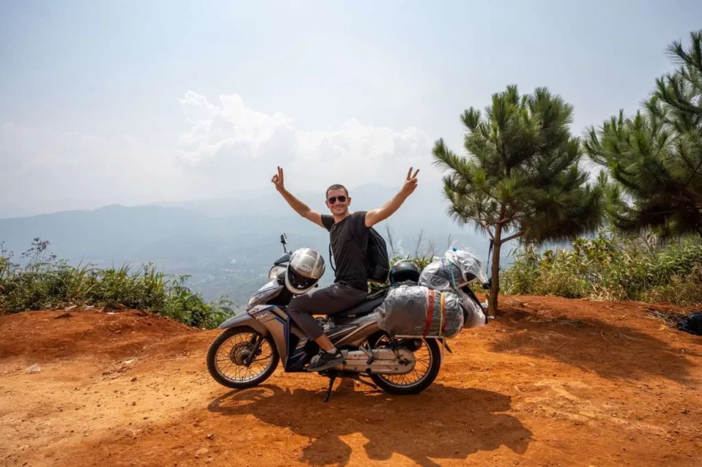 Jonathan sitzt auf einem Motorrad und zeigt dabei das Peace-Zeichen beim Vietnam Backpacking.