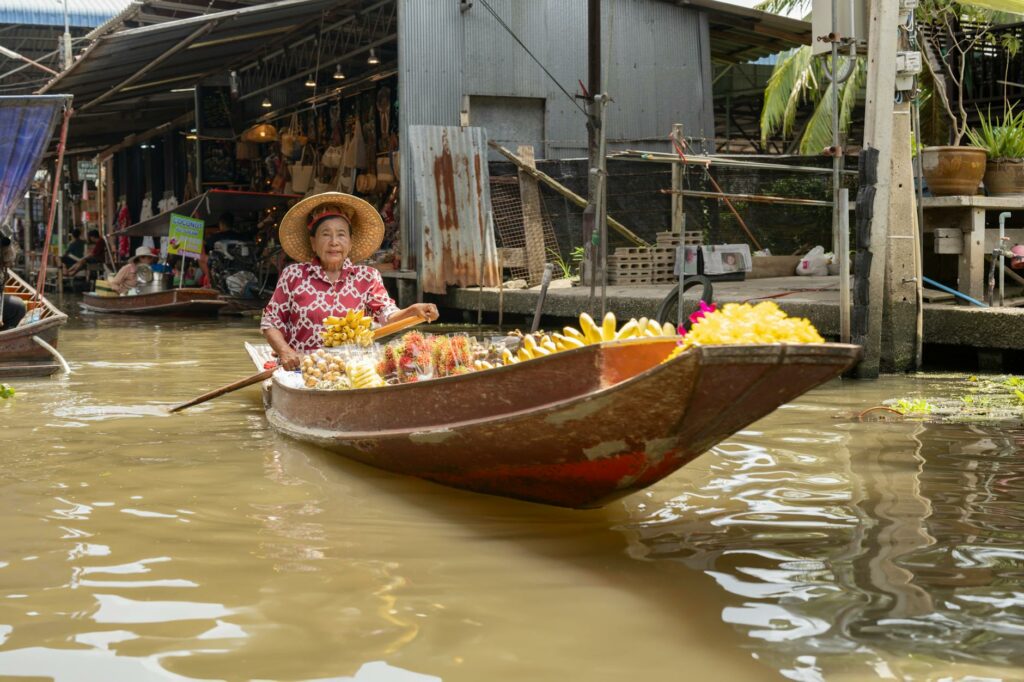 Schwimmender Markt in Thailand mit traditionellen Booten und frischem Obst, ein Highlight im Thailand Urlaub.