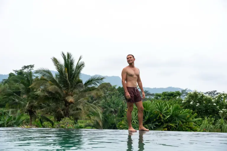 Jonathan an einem wunderschönen Infinity-Pool auf der Bali Backpacking Reise, umgeben von Dschungel und Reisfeldern.