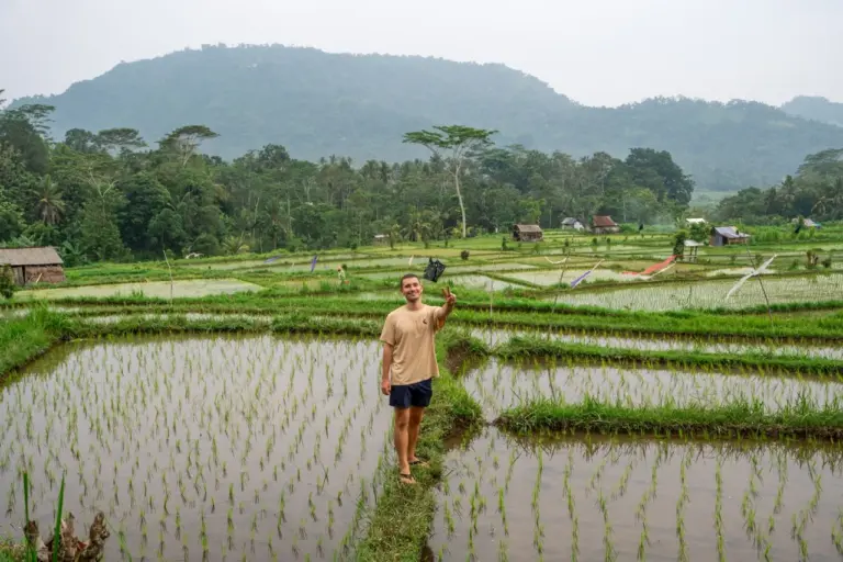 Jonathan auf einem grünen Reisfeld im Landesinneren von Bali, einem echten Geheimtipp auf der Bali Reiseroute mit wenigen Touristen.