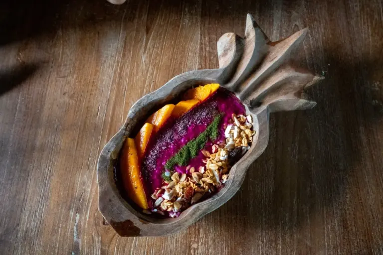 Bunte Smoothie-Bowl mit Orange, Granola und Samen in einer einzigartigen balinesischen Ananas-Schale. 