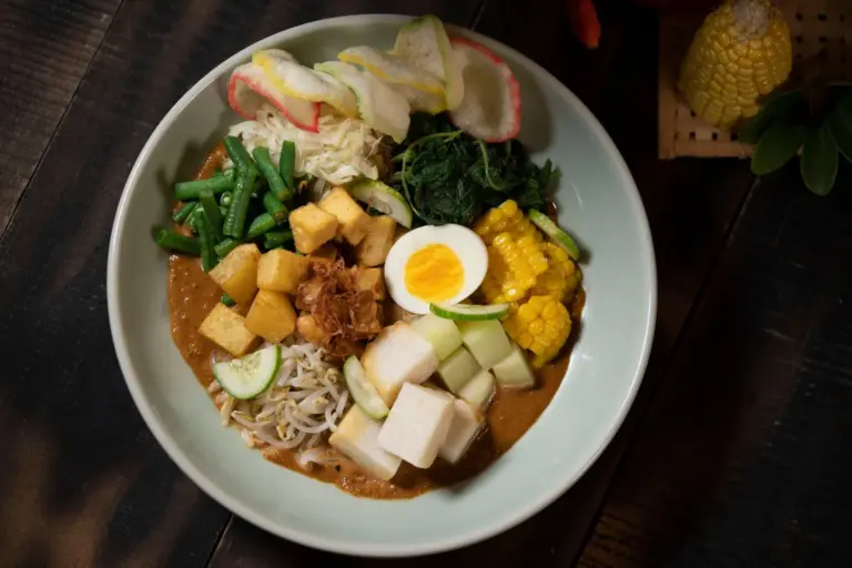 Ein Gado-Gado-Teller mit frischem Gemüse, Tofu und pikanter Erdnusssauce präsentiert die lebendige Rucksackküche Balis.