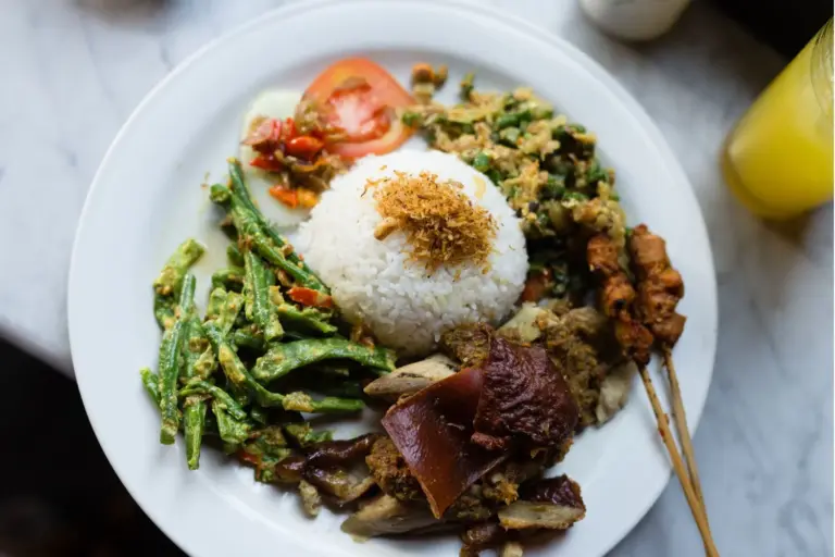 Ein leckeres Nasi Goreng, eines der beliebtesten Gerichte in Indonesien, serviert mit Reis, Satay und Gemüse.