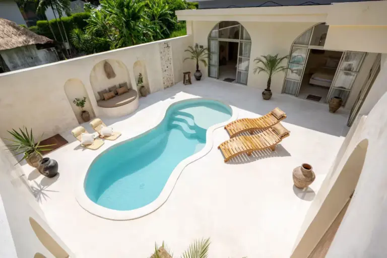Ruhiger Innenhof im Bali-Stil mit elegantem Pool, gemütlichen Liegestühlen und üppigem Grün als eines der besten Hotels in Canggu.