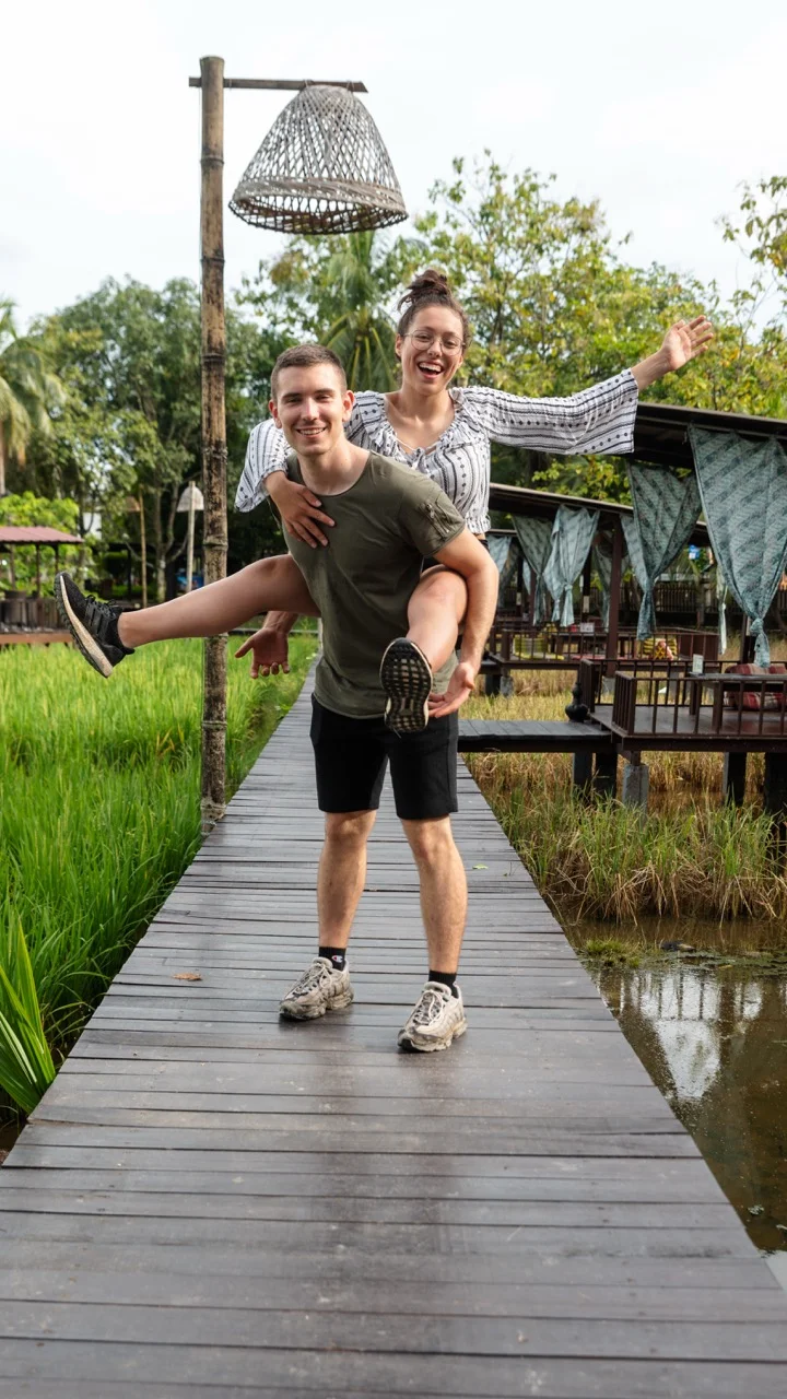 Clara und Jonathan lächeln auf einem üppigen Holzpfad in Malaysia (Borneo).