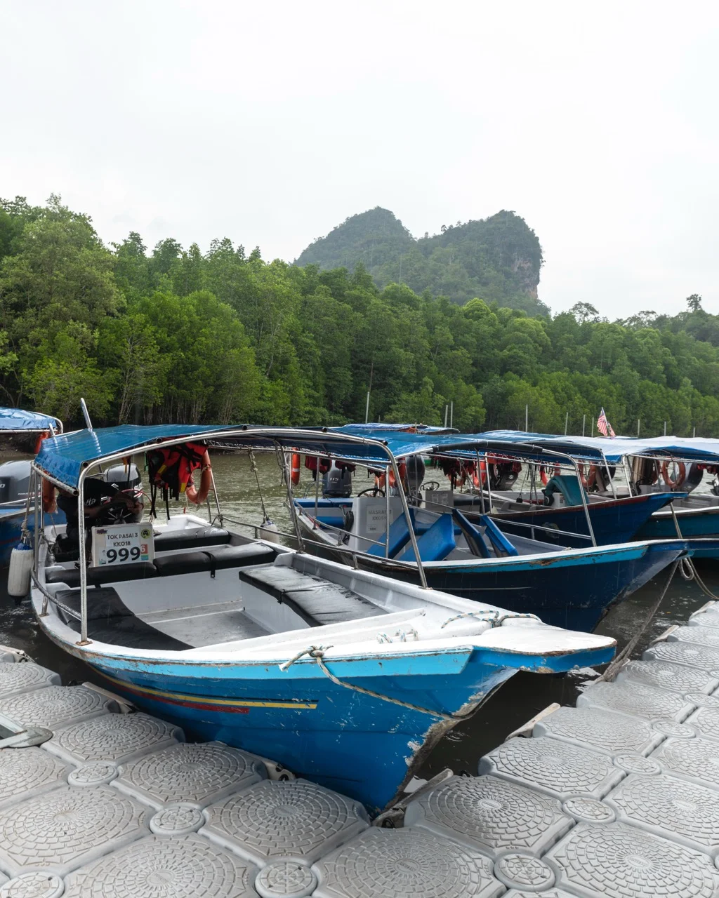 Blaue Boote am Steg für die Mangroven-Tour im Kilim Geopark auf Langkawi