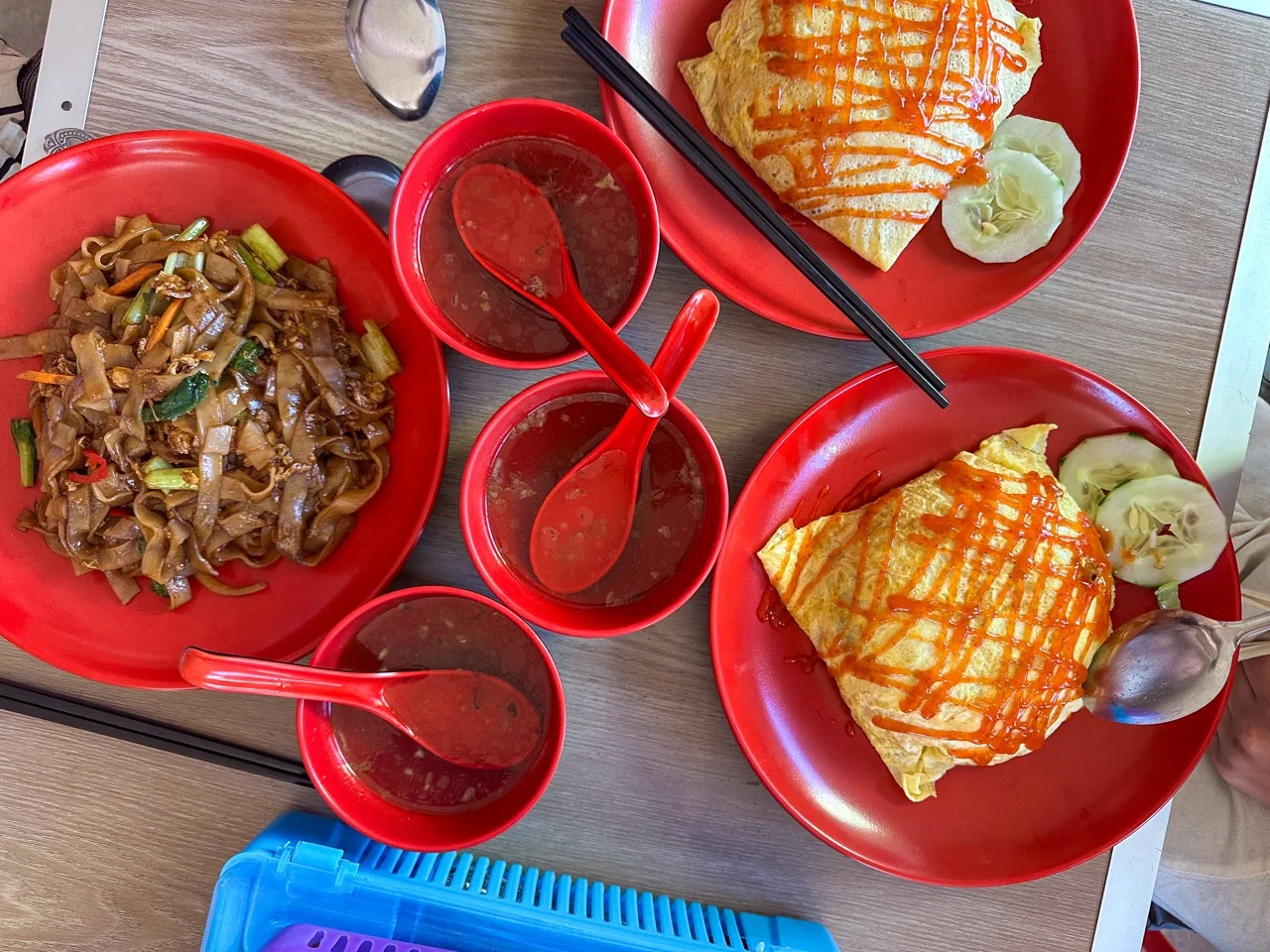 Char Kway Teow und Roti auf roten Tellern an einem Hawker-Stand in Penang