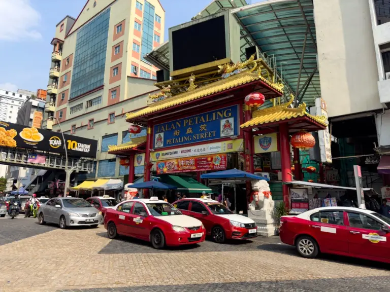 Der Eingang zur Petaling Street in Kuala Lumpur mit bunten Fassaden und einem Taxi auf der Rundreise durch Malaysia.