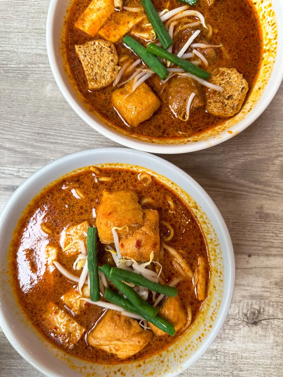Zwei Schalen Curry Laksa mit Tofu auf einem Tisch in Kuala Lumpur