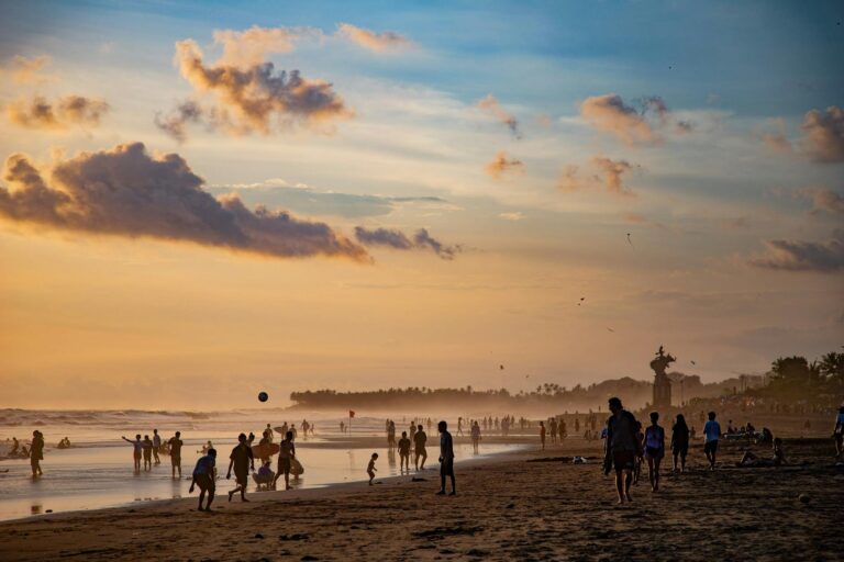 Urlauber genießen den Sonnenuntergang mit goldenem Licht in Canggu am Strand auf ihrer Bali Backpacking Reise.