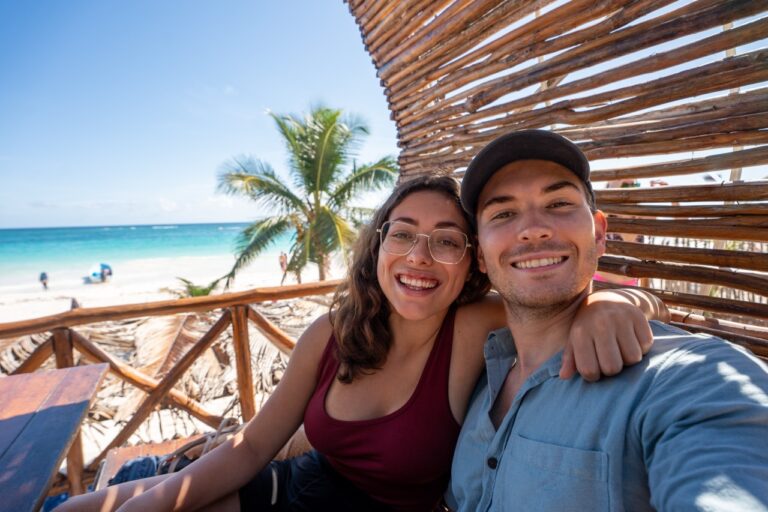 Clara und Jonathan genießen das lebhafte Strandleben im trendigen Café und planen ihre ideale Reise „Reiseziel 2025“.