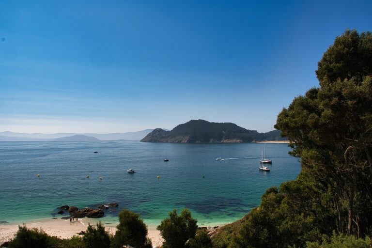 Ruhige Bucht mit Booten, glitzerndes Wasser, Sandstrand unter einem strahlend blauen Himmel – der perfekte Urlaub 2025.