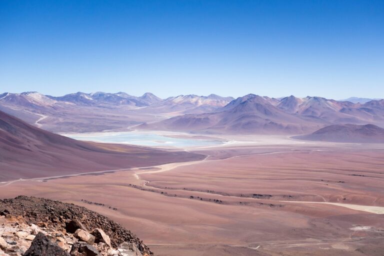 Weite Wüste mit schroffen Bergen und einem schimmernden See, ideal für eine aufregende Urlaubsreise 2025.