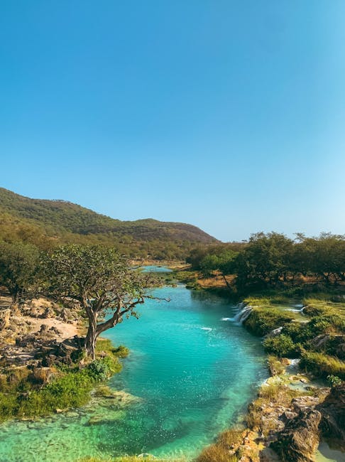 Türkisfarbener Fluss schlängelt sich durch grüne Hügel, ideal für den Sommerurlaub 2025 unter einem sonnigen Himmel.