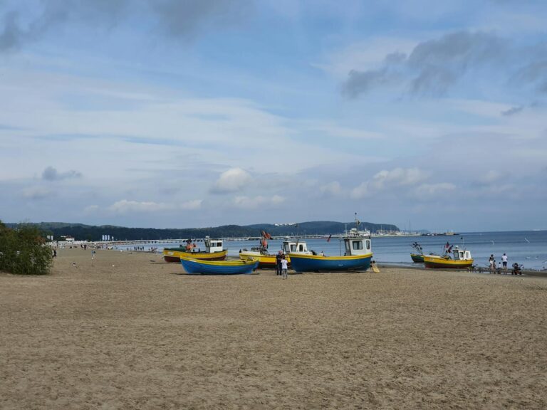 Sandstrand mit bunten Booten und Touristen genießen die wolkige Küste – ideal für den Sommerurlaub.