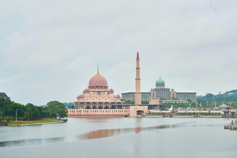 Die schöne Putra-Moschee mit der rosa Kuppel an einem ruhigen See unter bewölktem Himmel in Malaysia.