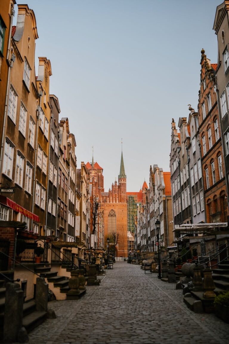 Charmante europäische Straße gesäumt von hohen, schmalen Gebäuden und einer Kirche, ideal für einen Sommerurlaub.