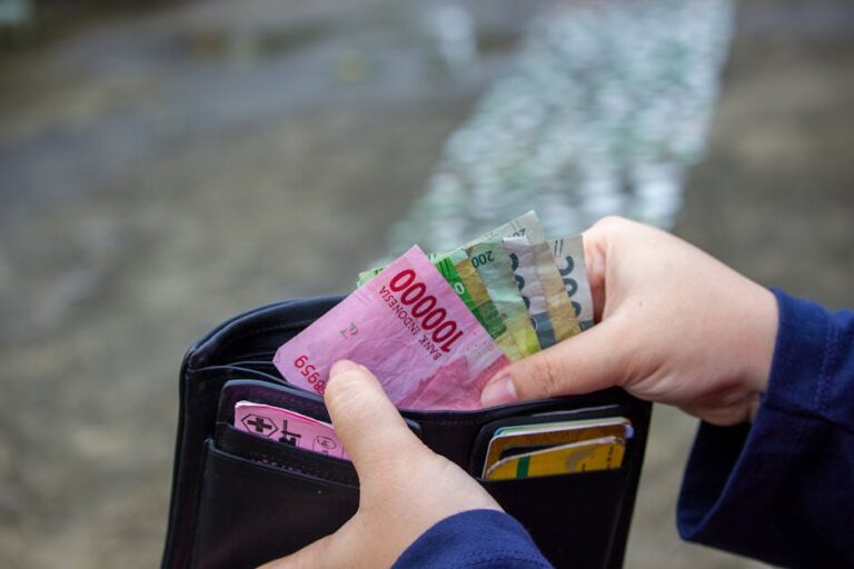 Jonathan hält eine offene Brieftasche mit Rupiah-Banknoten in der Hand, bereit für Abenteuer vor einer Koffer-Testreise.