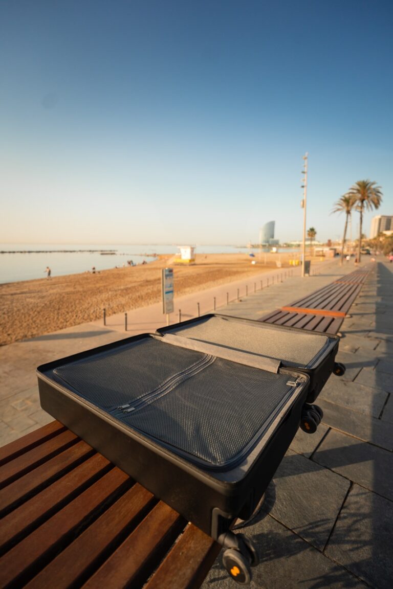 Der große Level 8 Koffer Test: Ein leerer Koffer liegt offen auf einer Bank an der Strandpromenade mit Blick aufs Meer.
