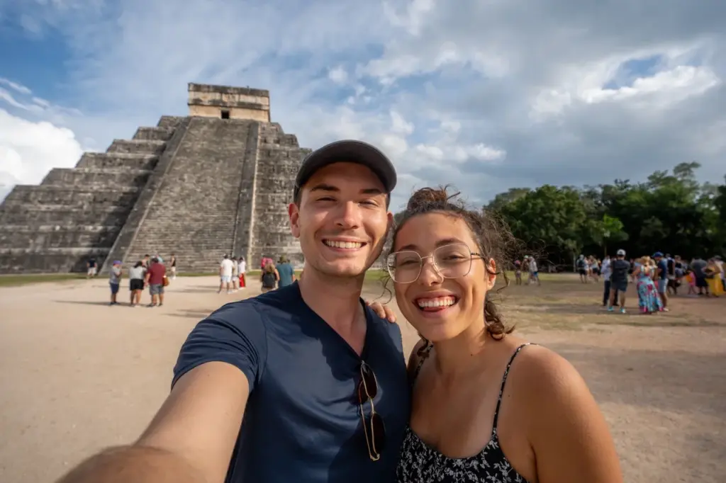 Clara und Jonathan lächeln gemeinsam vor der berühmten Pyramide von Chichen Itza in Yucatan, Mexiko.