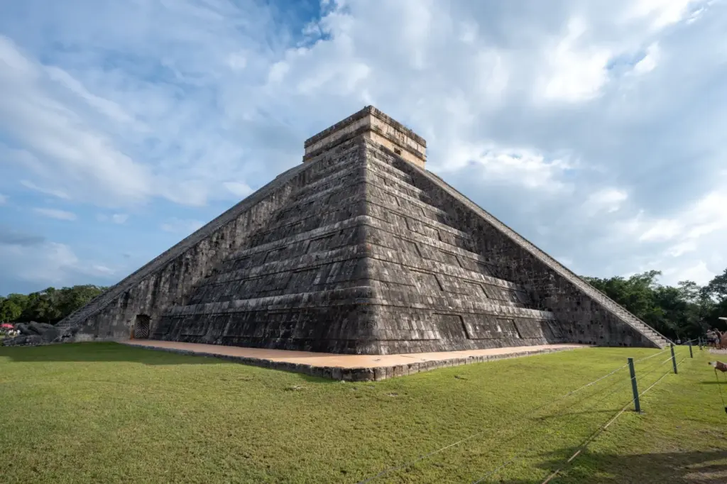 El Castillo, eine große Stufenpyramide in Yucatan, erhebt sich unter einem teilweise bewölkten Himmel.