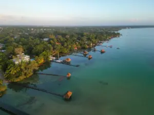 Luftaufnahme eines ruhigen Yucatan-Sees mit hölzernen Anlegestellen und gemütlichen Hütten am Seeufer, Mexiko-Reiselandschaft.