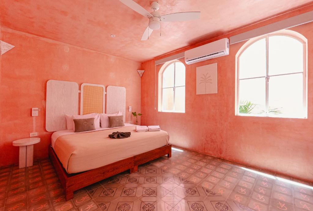 Gemütliches Schlafzimmer mit rosafarbener, strukturierter Wand und gefliestem Boden, ideal für eine Nacht auf der Yucatan Rundreise