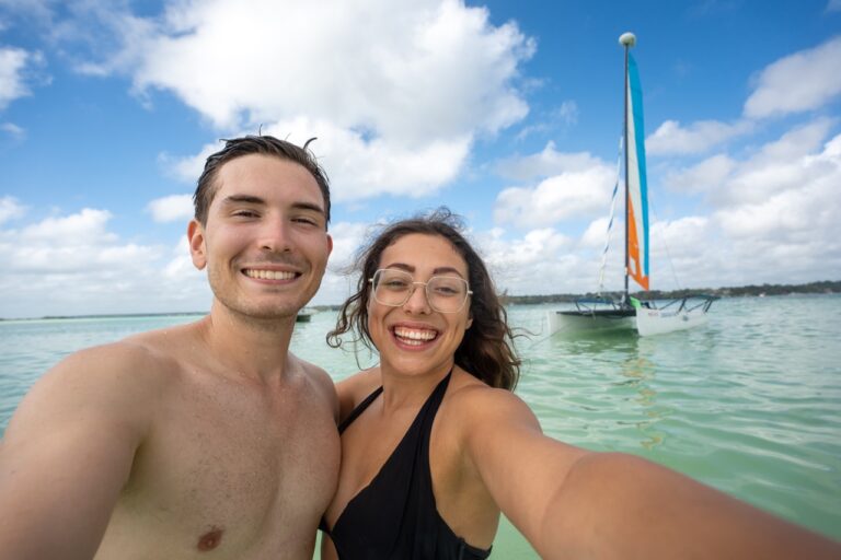 Clara und Jonathan stehen im flachen Wasser auf der Yucatan Rundreise vo einem Segelbooten.