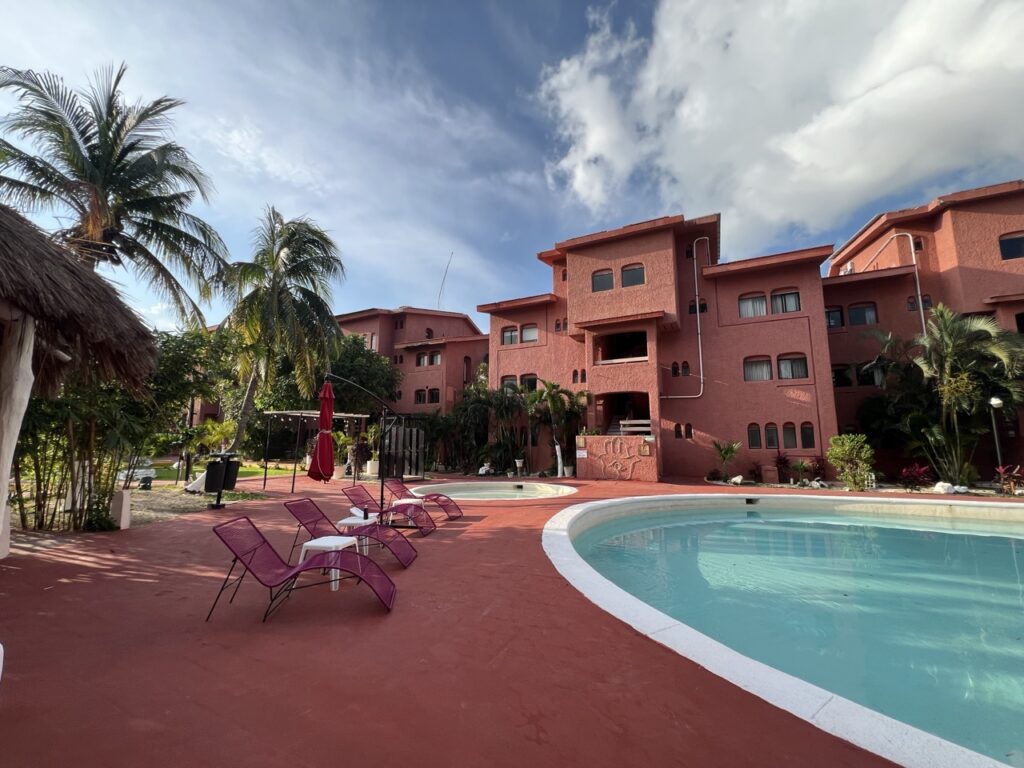 Außenpool mit roten Liegestühlen neben einem roten Hotel auf der Yucatan Rundreise