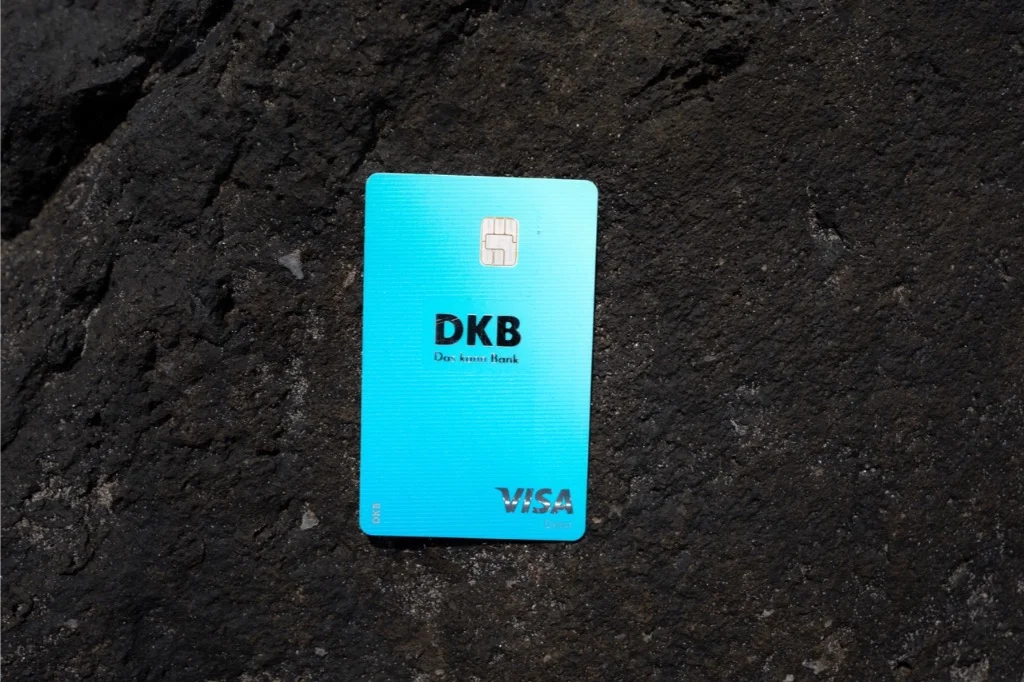 Eine blaue DKB Visa Reisekreditkarte Kostenlos liegt auf einem zerklüfteten dunklen Felsen, perfekt für Reiseabenteuer.