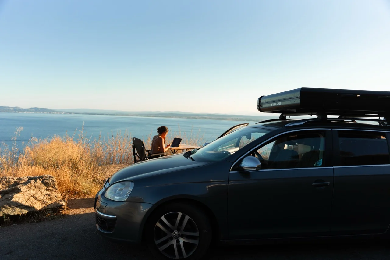 Auto mit aufgebautem Dachzelt am See bei Sonnenuntergang