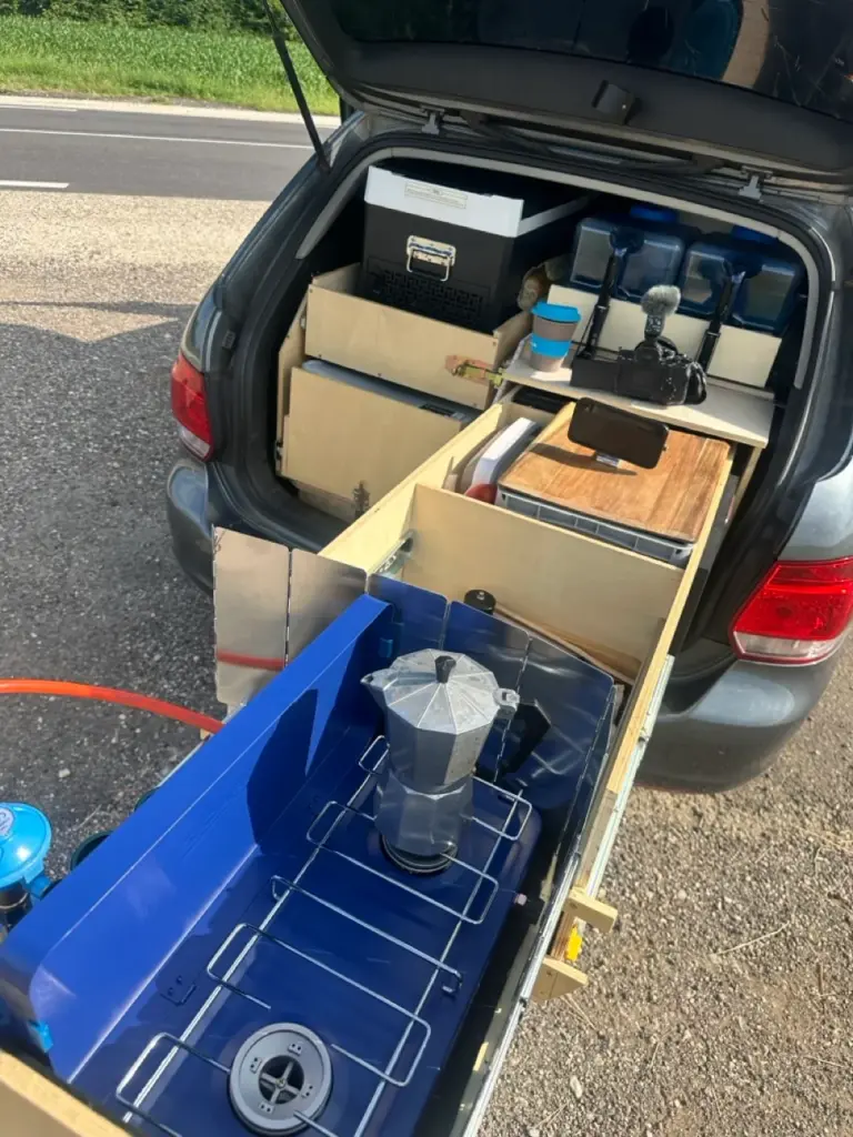 Im Kofferraum befindet sich eine praktische, ausziehbare Campingküche, die sich hervorragend für Roadtrips mit dem Dachzelt eignet.