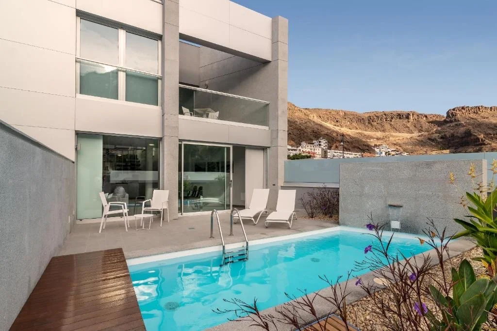 Schicke Villa auf Gran Canaria mit privatem Pool, bequemen Stühlen auf der Terrasse und atemberaubendem Bergblick.