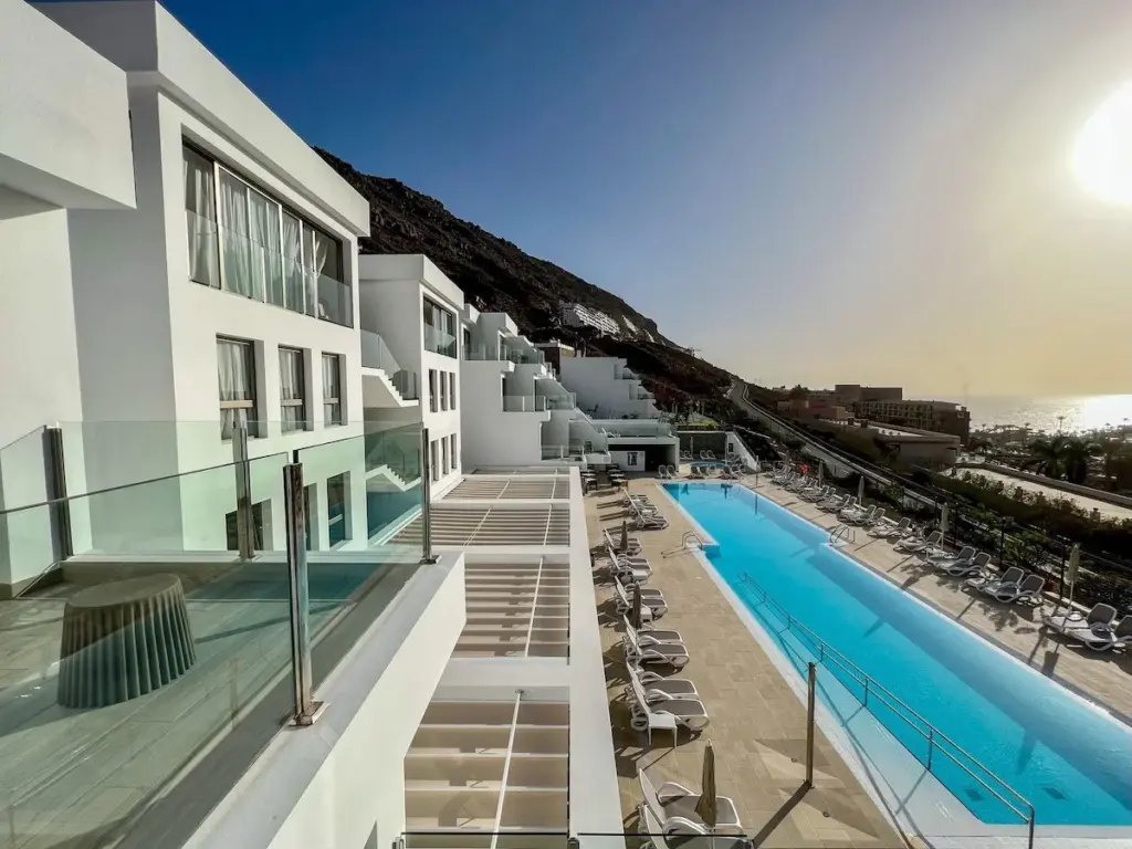 Modernes Strandhotel mit Balkonen, langem Pool und Meerblick bei Sonnenuntergang auf Gran Canaria.