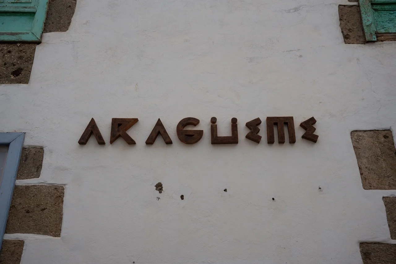Braune geometrische Buchstaben ARAGUEME auf einer weißen Stuckwand mit Steinakzenten auf Gran Canaria, Spanien.