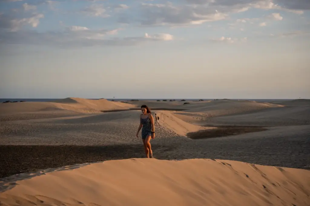 Die goldenen Sanddünen von Maspalomas, Gran Canaria, leuchten bei Sonnenaufgang oder Sonnenuntergang unter einem bewölkten Himmel.