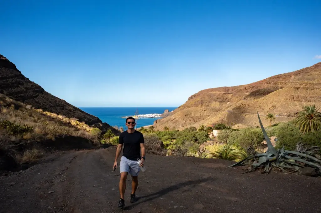 Jonathan auf einem unbefestigten Weg in den Hügeln von Gran Canaria mit Blick auf das Meer und den blauen Himmel im Hintergrund.