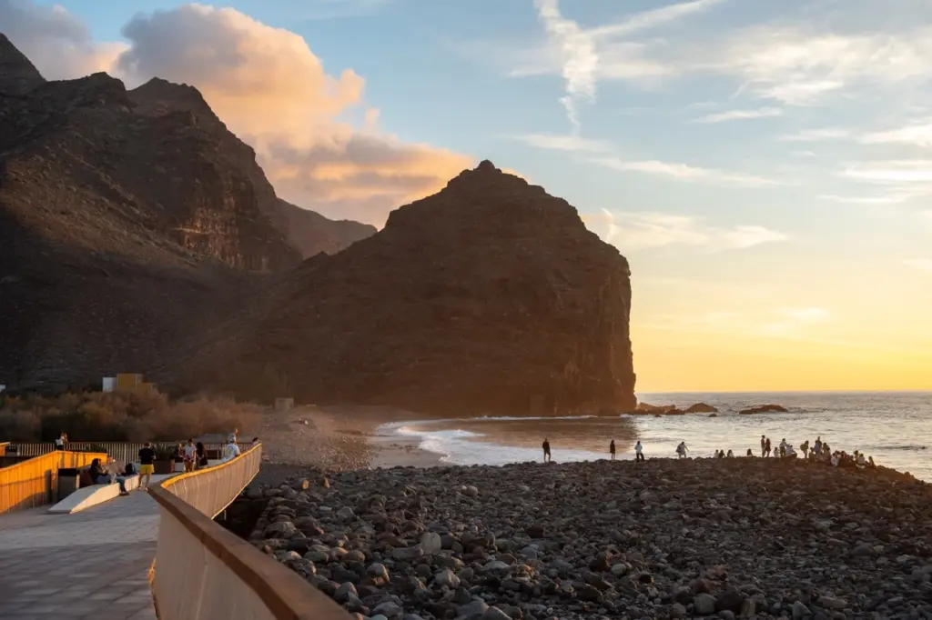 Der felsige Strand von Gran Canaria bei Sonnenuntergang mit ruhigen Wellen und Klippen, goldenem Licht, das die atemberaubende Aussicht unterstreicht.