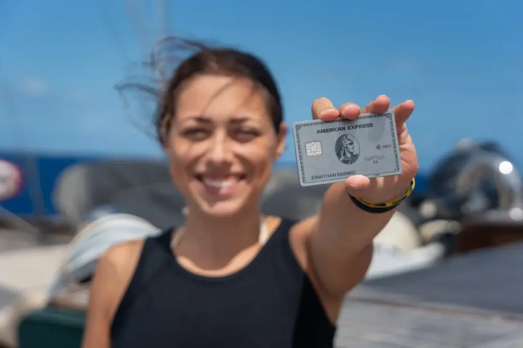 Clara hält die silberne Amex Platin in ihrer Hand auf einem Segelboot.