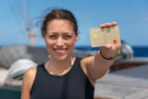 Clara hält die TF Mastercard Gold in der Hand auf hoher See beim Segeln.