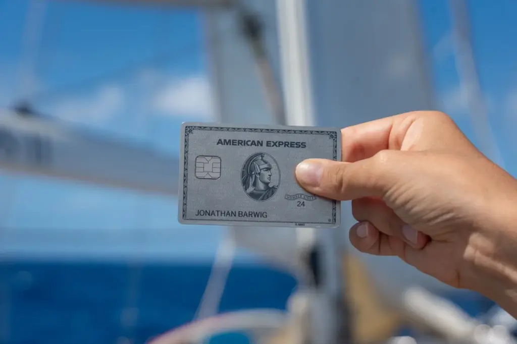 Die AMEX Platinum als Premium Kreditkarte vor Segeln und unter blauem Himmel. 